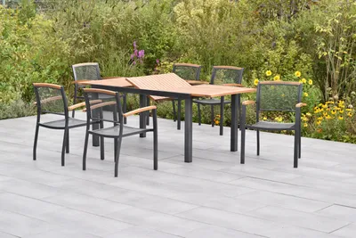 A garden dining set with a table and chairs on a patio, surrounded by lush greenery and flowers.