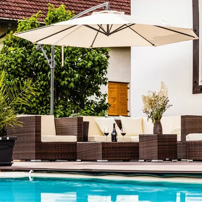 An outdoor patio furniture set with a large umbrella next to a swimming pool.