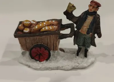 Eine kleine Figur, die einen Bäcker darstellt, der einen Karren voller Brot und Brötchen zieht.