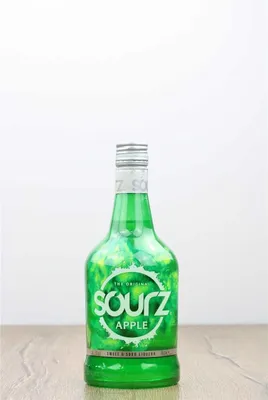 A bottle of Sourz Apple liqueur is placed on a wooden surface against a white background.