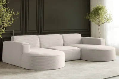 A cream-colored sectional sofa with a corduroy texture is placed in a modern living room with dark paneled walls and a light rug.
