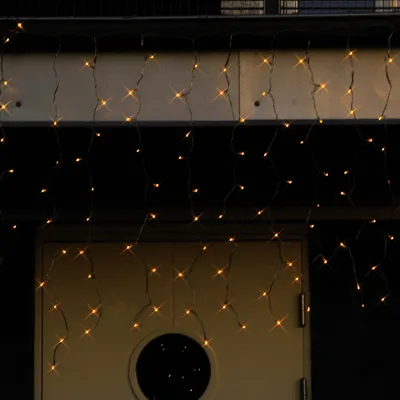 A close-up shot of icicle-shaped LED lights hanging in front of a building.