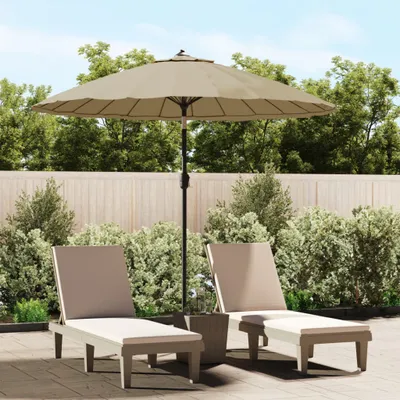 Two lounge chairs and a patio umbrella are set up on a patio with a wooden fence and lush greenery in the background.