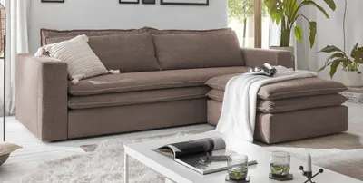 A brown sectional sofa with a chaise lounge and an ottoman in a living room setting.
