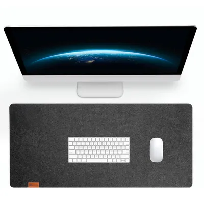 A computer monitor is shown above a desk mat with a keyboard and mouse on it.