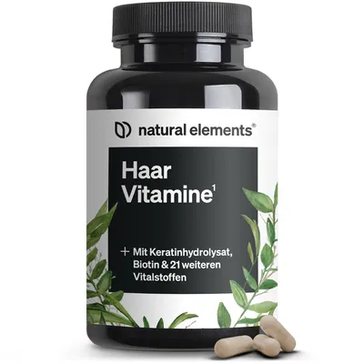 A bottle of hair vitamins with some leaves and capsules in the foreground.