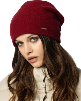 A woman wearing a burgundy beanie and a cream jacket.