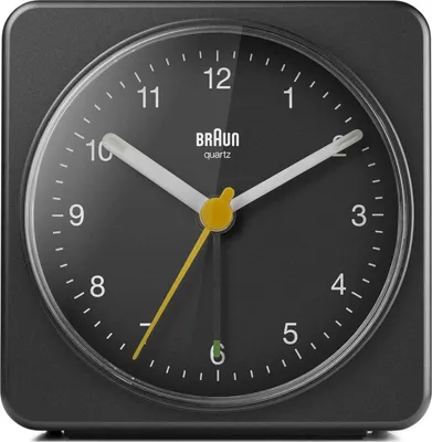 A close-up, front-facing view of a black Braun analog alarm clock.