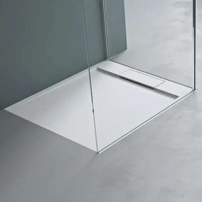 A modern shower tray with glass enclosure in a minimalist bathroom setting.