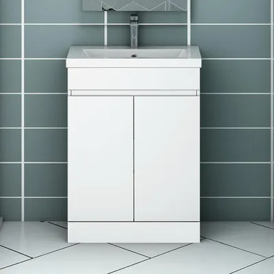 A white bathroom vanity with a sink and faucet against a tiled wall and floor.