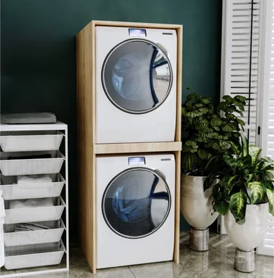 A laundry room with a stacked washer and dryer unit, laundry baskets, and plants.
