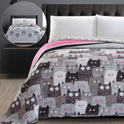 A close-up view of a blanket with a cat print, laid out on a bed.