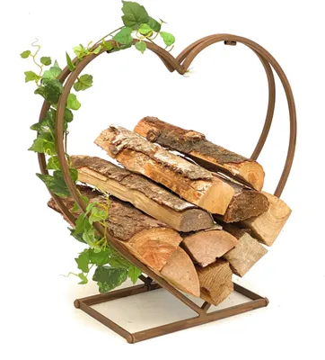 A heart-shaped metal log holder filled with firewood, decorated with artificial ivy.