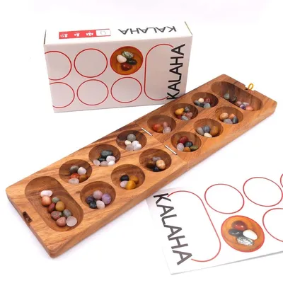 Kalaha-Steinchenspiel mit Verpackung und Spielanleitung, Holzbrett mit Mulden und farbigen Bohnensteinen.