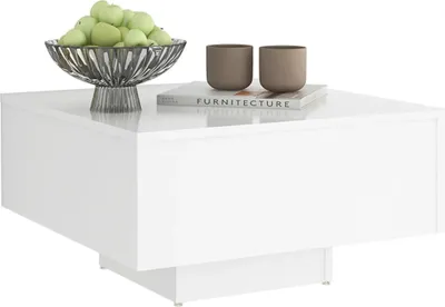 A white square coffee table with decorative items on top.