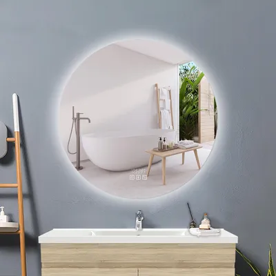 A modern bathroom with a round LED mirror reflecting a bathtub and an outdoor view.