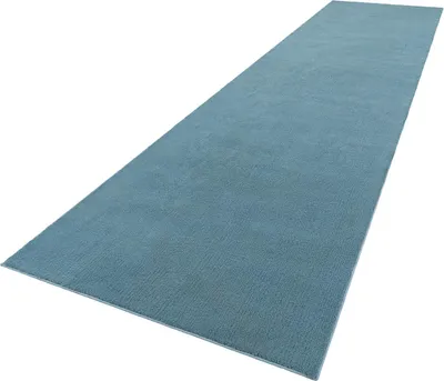 A long, narrow blue rug is shown from a diagonal angle against a white background.