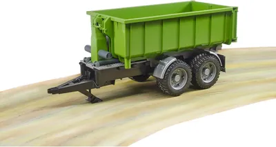 A green trailer with black accents sits on a tan surface.