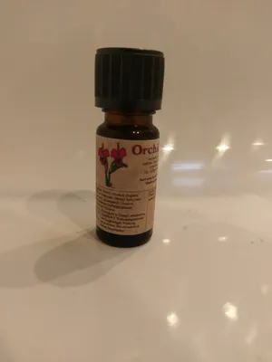 Kleine braune Flasche mit einem schwarzen Verschluss. Auf dem Etikett steht "Orchidee".