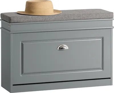 A gray shoe cabinet with a cushioned top and a straw hat placed on top.
