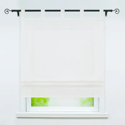 A white Roman blind is shown hanging in front of a window, with a hint of green foliage visible outside.