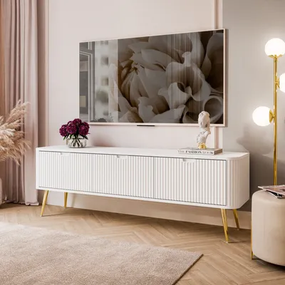 A modern living room with a TV stand, TV, lamp, and decor.