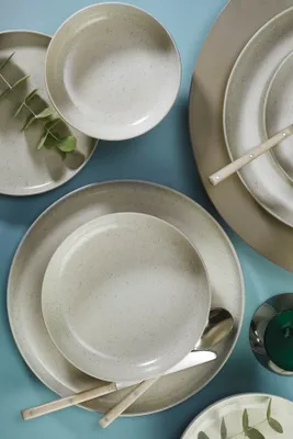 A top-down view of a set of ceramic dishes arranged on a blue surface.