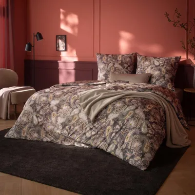 A bedroom scene with a bed dressed in paisley patterned bedding.