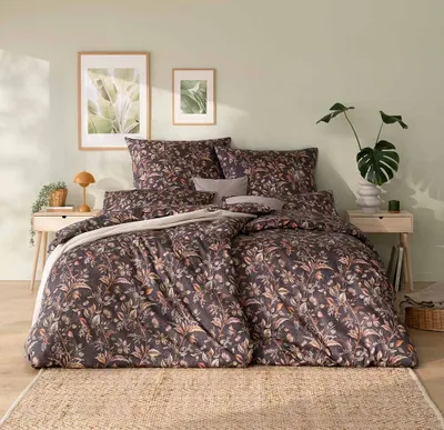 A bedroom scene with a bed dressed in floral patterned bedding, bedside tables, and artwork on the wall.