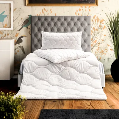 A neatly made bed with a white duvet and pillows, set against a decorative wallpaper and a tufted headboard.