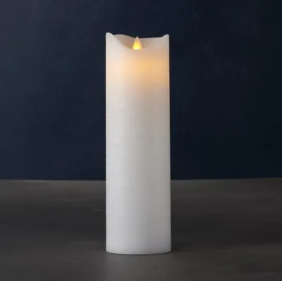 A white LED candle with a flickering flame sits on a dark surface against a dark blue background.