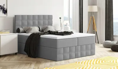 A modern bedroom scene with a large upholstered bed as the main focus.