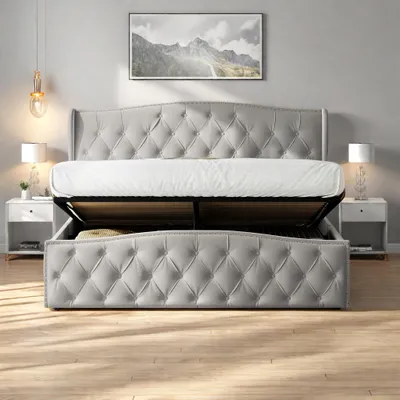 A tufted grey bed with its storage compartment open, revealing stored items, set in a bedroom with nightstands and lamps.
