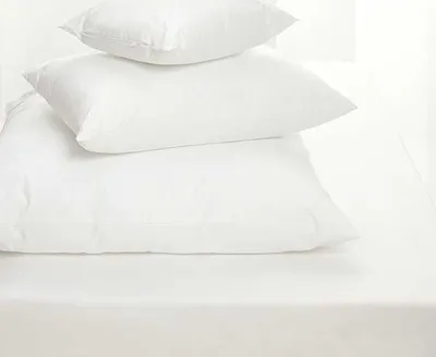 A stack of three white pillows on a white surface.