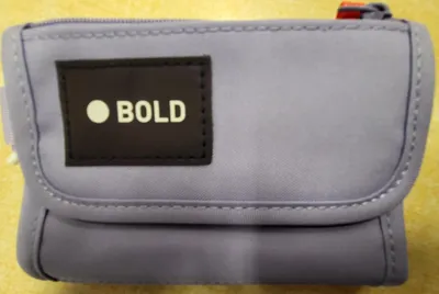 A lavender colored wallet with a black label that says 'BOLD' in white text.
