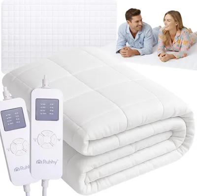 A folded electric mattress topper with two controllers is shown, with a couple lying on a bed in the background.
