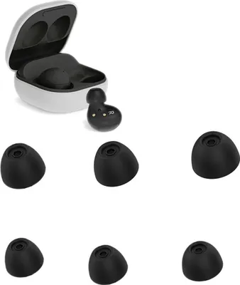 A white charging case for wireless earbuds is open, with one earbud inside and another beside it. Six black silicone ear tips are arranged below the case.