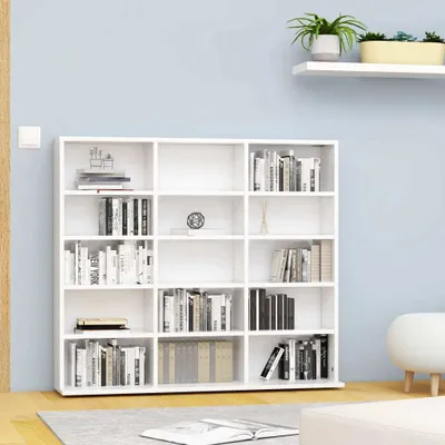 A white bookshelf filled with books, placed against a light blue wall.