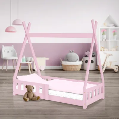 A child's pink tipi-style bed with bedding and a teddy bear in a nursery setting.