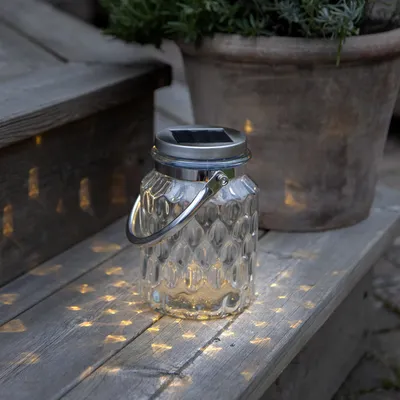 A solar-powered lantern sits on a wooden surface, casting patterned light.