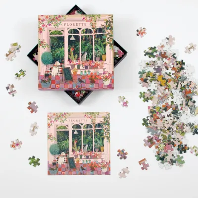 A jigsaw puzzle box and scattered puzzle pieces on a white background.