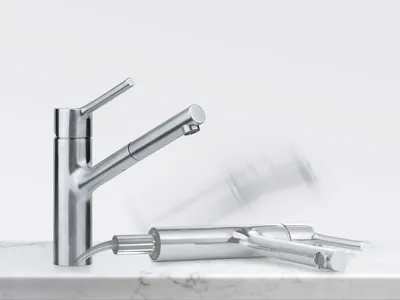 A stainless steel kitchen faucet is shown on a marble countertop against a white background. Another faucet is lying down in front of it, with motion blur indicating movement.