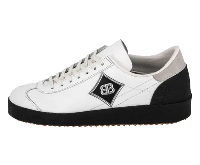 A side view of a white sneaker with a black sole and a diamond-shaped logo on the side.