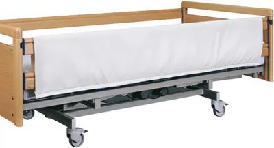 A hospital bed with wooden side rails and a white padded bumper.