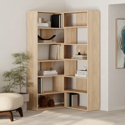 A corner bookshelf unit filled with books and decorative items, placed in a room setting with a plant and ottoman.