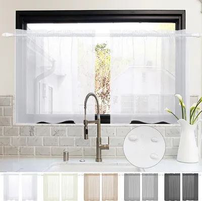 A kitchen window with white sheer curtains and a faucet.