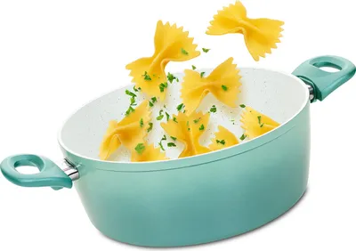 A turquoise pot with farfalle pasta and parsley falling into it.