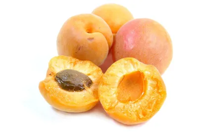 A group of apricots, with two cut in half to show the pit and flesh, on a white background.
