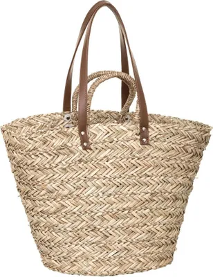 A straw shopping basket with brown leather handles against a white background.