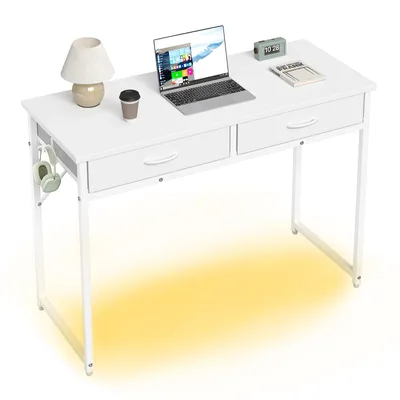A white desk with a laptop, lamp, coffee cup, and headphones.
